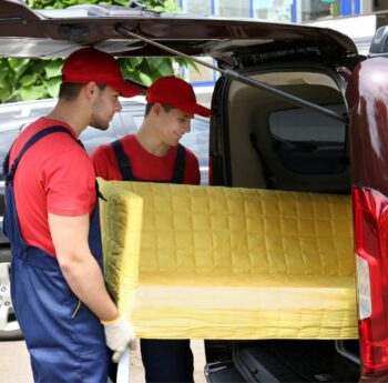 Günstig umziehen in Kleve Günstig umziehen in Kleve: Umzugshelfer laden ein gelbes Sofa in einen Transporter