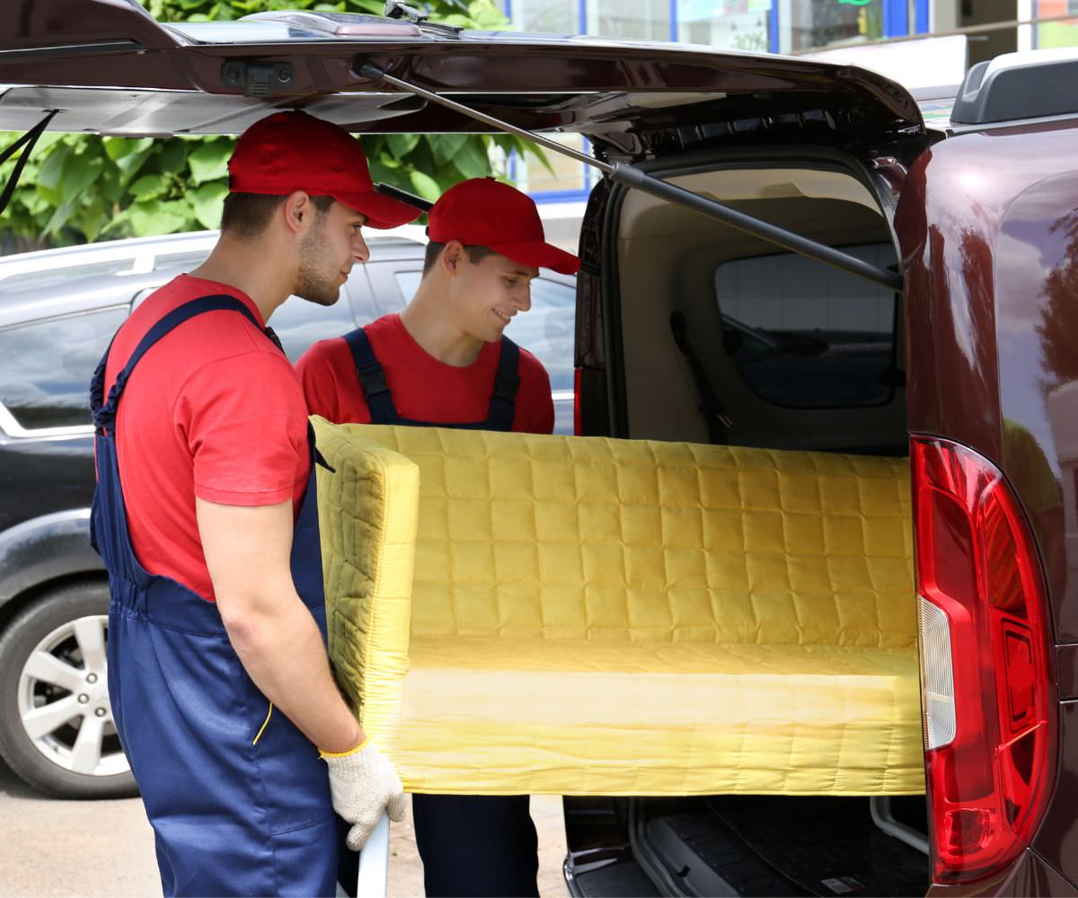 Umzugshelfer laden ein gelbes Sofa in einen Transporter – Preiswert umziehen Kleve