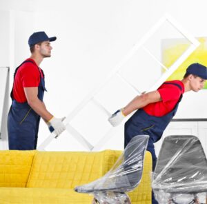 Umzug in Kleve Zwei Helfer tragen ein Möbelstück an einem gelben Sofa vorbei – Umzug in Kleve