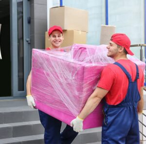Möbel in Schutzfolie Zwei Umzugshelfer tragen ein in Folie gepacktes Möbelstück