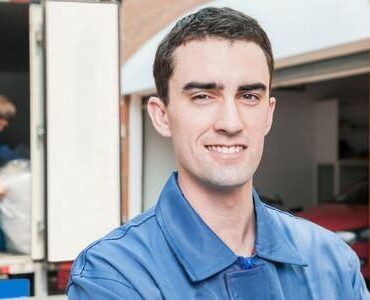 Umzugshelfer Kleve Lächelnder Umzugshelfer vor einem Transporter – Umzugshelfer Kleve